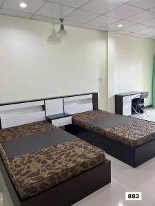 een kamer met 2 bedden en een bureau bij Jaroon House in Samutprakarn