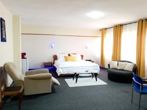 a hotel room with a bed and two chairs at Hôtel particulier HP in Conakry