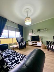 a living room with a couch and chairs and a television at A casa da Sia in Ribadeo