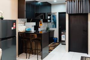 a kitchen with black cabinets and a bar with stools at S&A Homestay in Sungai Petani