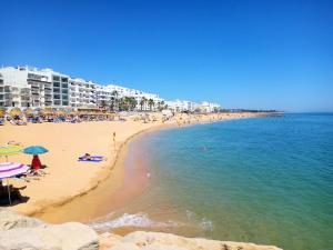 a beach with people and buildings and the ocean at Quarteira Stylish 2 by Homing in Quarteira