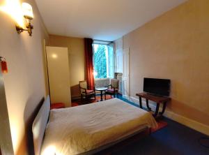 a hotel room with a bed and a television at De la Maison Restau' à la Chambre en particulier in Voreppe