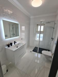a white bathroom with a sink and a toilet at VILLA DO LIMAO in Tavira