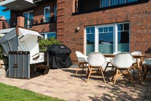 a grill and chairs in front of a brick building at KÖ-Gartensuite in Westerland