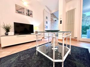 a living room with a tv and a glass table at Villa Seashell in Lignano Sabbiadoro