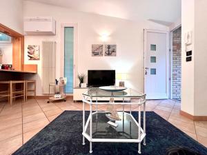 a living room with a glass table and a tv at Villa Seashell in Lignano Sabbiadoro
