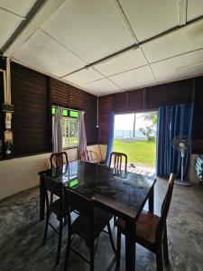 una sala da pranzo con tavolo, sedie e una finestra di Balek Kualé a Kampong Baru
