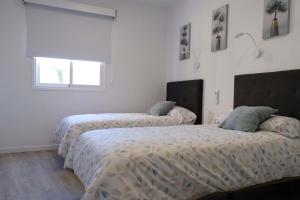 two beds in a room with white walls and a window at JVG VILLAS - Villa Giulia in Güimar +14 photos