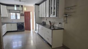 a kitchen with white cabinets and a black counter top at Moalafivilla Properties, Block 10, 3 Beds House in Gaborone +4 photos