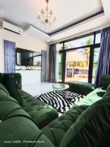 a living room with a green couch and a table at AWA Pool Villa in Ban Huai Yai