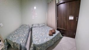 una camera con due letti e un armadio di Apartamento Residencial Angélica em Guarapari a 150m do mar a Guarapari
