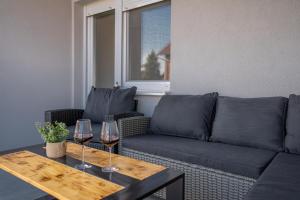 a living room with a couch and two glasses of wine at Apartman Kačićeva in Vukovar