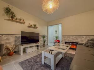 a living room with a couch and a tv and a fireplace at Villa Bel Air - appartement avec jardin et parking in Chartres