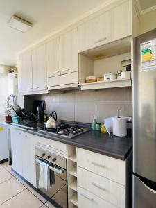 a kitchen with white cabinets and a stainless steel refrigerator at Depto 941 in La Serena +6 photos