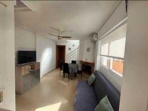 Una sala de estar con un sofá y una mesa con sillas. en Adosado con piscina al lado de la playa, en Santa Pola