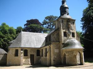 an old stone building with a tower with a clock on it at Les gîtes du Mesnil chambre standard in Équemauville