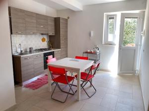 a kitchen with a white table and red chairs at Casalago in Bolsena
