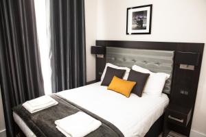 a bedroom with a bed with black and white pillows at The Tudor Inn Hotel in London