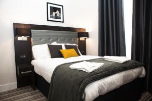 a hotel room with a large bed with yellow pillows at The Tudor Inn Hotel in London