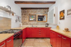 a red kitchen with a stove and a sink at Casa Belinda in Vrboska +22 photos