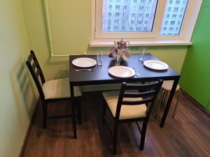 a dining room table with two chairs and a table with plates and glasses at Plavnieku apartment in Riga