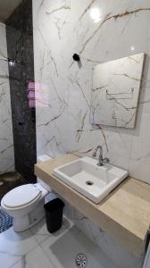 a bathroom with a sink and a toilet and a mirror at Descanso - Casa de Praia in Mongaguá +18 photos