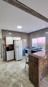 a large kitchen with a refrigerator and a table at Descanso - Casa de Praia in Mongaguá