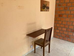 a wooden table and a chair next to a wall at Quartos com banheiro compartilhado em Araguaína in Araguaína