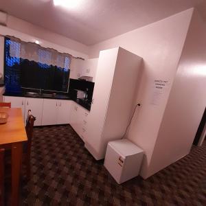 une cuisine avec des armoires blanches et une télévision sur un mur dans l'établissement bestwest apartments, à Nadi