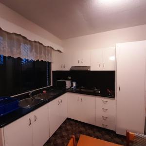 une cuisine avec des armoires blanches, un évier et une fenêtre dans l'établissement bestwest apartments, à Nadi