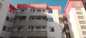 a tall white building with red roofs and balconies at Kanaprime Hotels & Safaris Mtwapa Gem in Mtwapa