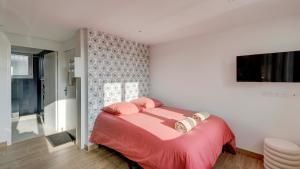 a bedroom with a bed with pink sheets and a television at Le Littoral - Appart'Escale in Saint-Nazaire