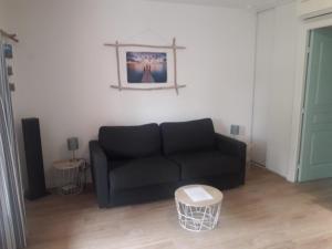 un soggiorno con un divano nero e un tavolo di Appartement 30m2 avec jardin et piscine chauffée à La Palmeraie Grimaud a Grimaud