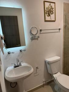 uma casa de banho com um lavatório, um WC e um espelho. em Hotel Faava em Mazatlán