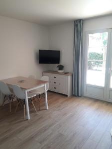 un soggiorno con un tavolo e una televisione di Appartement 30m2 avec jardin et piscine chauffée à La Palmeraie Grimaud a Grimaud