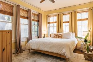 - une chambre dotée de murs jaunes et de fenêtres avec un lit dans l'établissement December Group Retreat 4BR Victorian Home, UT & Downtown, à Austin
