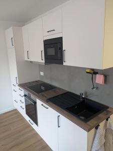 a white kitchen with a sink and a microwave at Schlosspark Apartments in Flechtingen