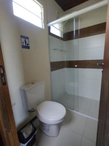 a bathroom with a toilet and a glass shower at Casas Paz e Amor Praia do Rosa Sunset e Sunrise in Imbituba