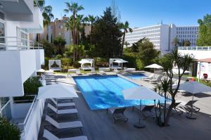 uma piscina com cadeiras e guarda-sóis num edifício em Apartamentos Vibra Tivoli em Playa d'en Bossa