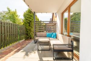 a patio with a couch and chairs on a balcony at Morski domek in Dębki