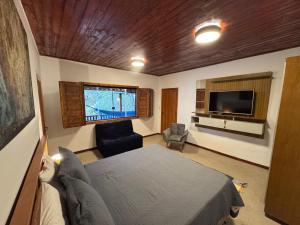 a bedroom with a bed and a tv and a couch at Pousada Kokopelli in Lavras Novas