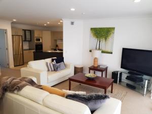 a living room with two white couches and a flat screen tv at Ocean Breeze Resort Pauanui in Pauanui