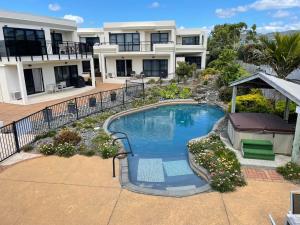 a swimming pool in front of a house at Ocean Breeze Resort Pauanui in Pauanui