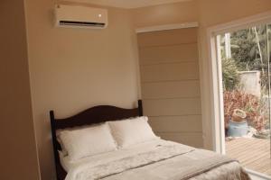 a bedroom with a bed with a window and a air conditioner at Suíte Santa Catarina in Pomerode