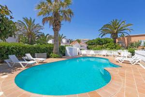 a swimming pool with chairs and palm trees at Villa Joel - Casa con piscina cerca de la playa in Son Carrio