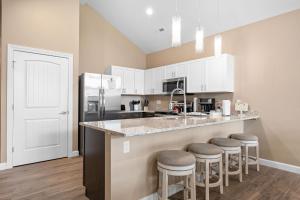 a kitchen with white cabinets and a counter with bar stools at Spacious Retreat, Heart of the City, Indoor Pool, Free Attraction Tickets! in Branson