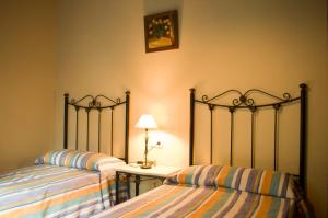 a bedroom with two beds and a table with a lamp at Rural Montes Málaga: Lagar Don Sancho in Málaga