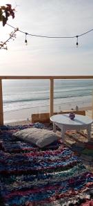 - une table blanche assise au-dessus d'un tapis sur la plage dans l'établissement The Trizit, à Taghazout