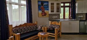a living room with a couch and a kitchen at 6 Engo Cottage - Benanda Forest Resort in Masaka