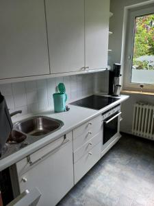 a kitchen with white cabinets and a sink and a window at Nicky's Place in Nürnberg